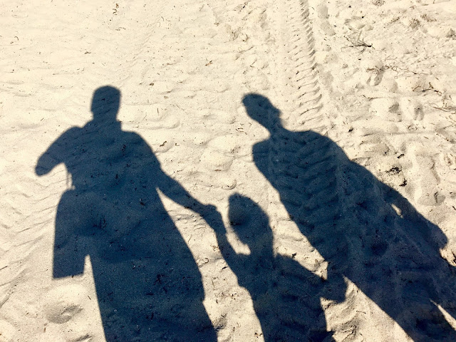 Shadow of two adults and one child in the sand at Miami Beach