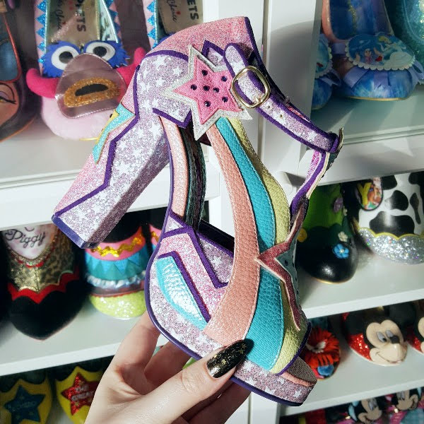 Irregular Choice Eres Hermosa shoe in hand with shoe shelves in background