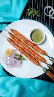 Serving chicken seekh kabab with green chutney onion ring and lemon