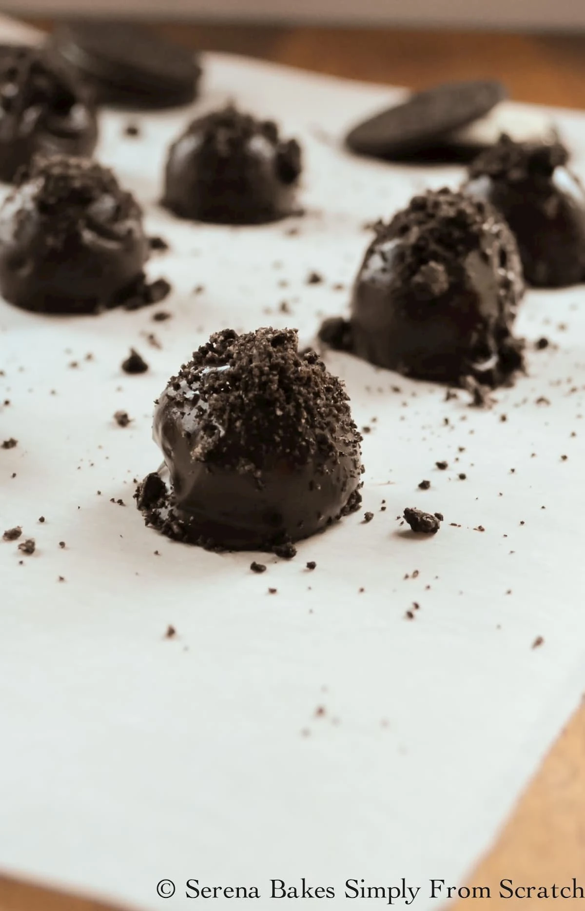 Mint Oreo Cookie Balls dipped in chocolate topped with crushed oreos on a white tray.