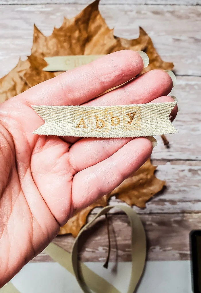 hand holding ribbon piece with stamped name