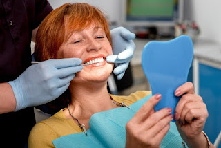 Dental professional holding a person's face and lips as they look in a hand held mirror