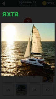 По волнам плывет красивая яхта под парусом на встречу яркому солнцу над горизонтом 