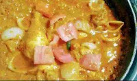 Cooking chicken do pyaza with cubes of onion, tomato and slits green chilli