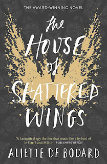 Yellow jagged splatters in the shape of large open angel wings, on a dark grey background.