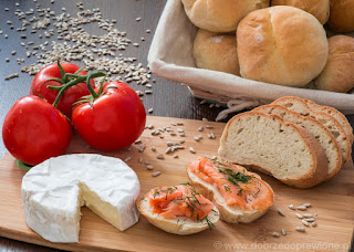 Domowe bułeczki z łososiem i koperkiem, nad desce z serem typu camembert i pomidorami