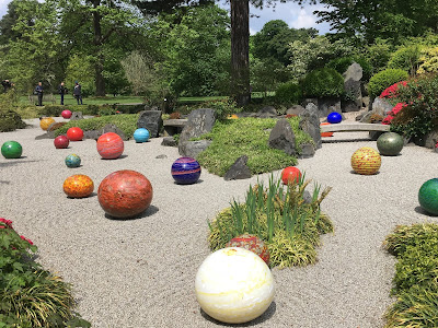 Photo showing raked grey gravel (Japanese garden) dotted with large glass spheres 