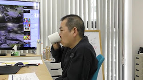 Yu sipping from his mug