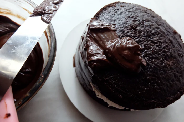 spreading chocolate ganache on cake
