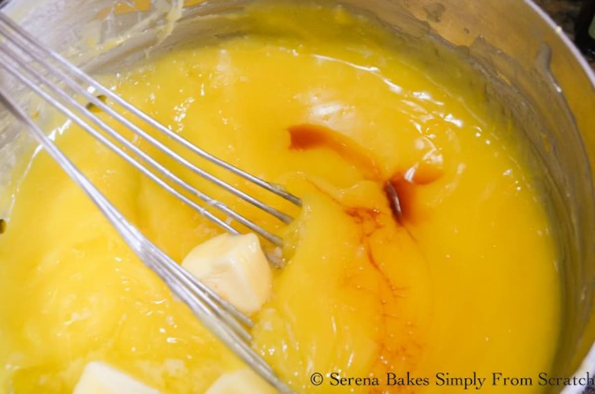 Lemon Meringue Pie Filling with butter and vanilla being stirred into a large saucepan.