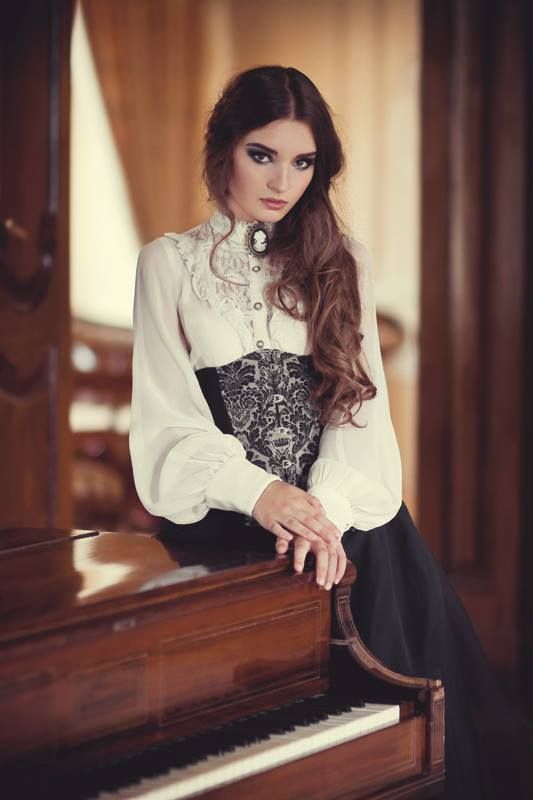 Woman wearing gothic victorian clothing (blouse, corset, skirt, cameo brooch) in elegant black and white