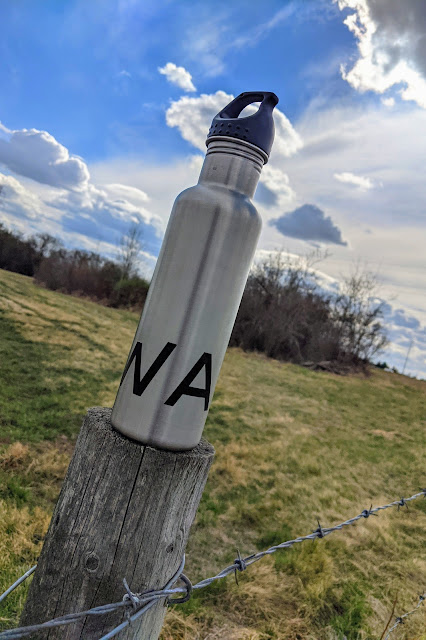 A worm's eye view of the walk stainless steel water bottle on a partly sunny day.