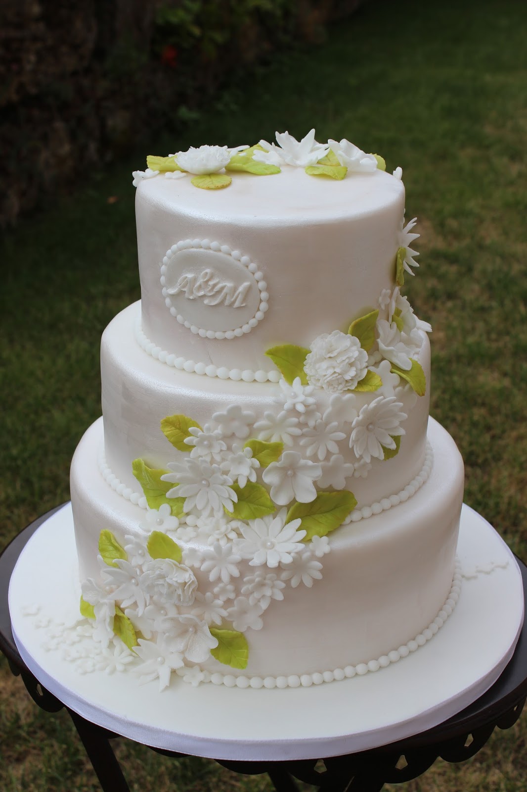 Hochzeitstorte in weiß mit kleinen Blümchen und hellgrünen Blättern ...