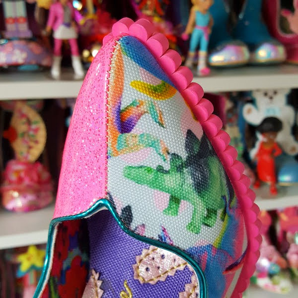 pointed toe of shoe close up in split fabric design with dinosaurs and pink glitter patent