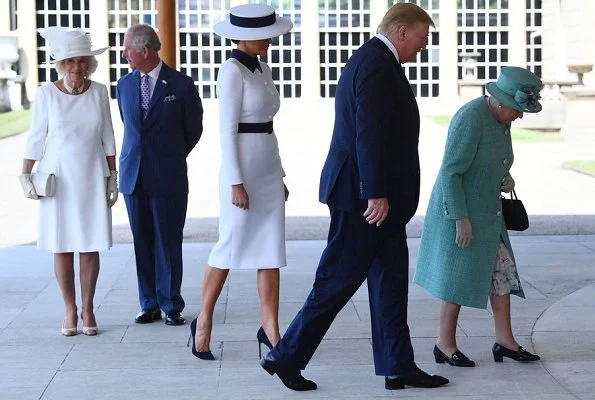 Melania Trump is wearing a custom white crepe dress with navy details by Italian fashion house, Dolce & Gabbana. Queen Elizabeth