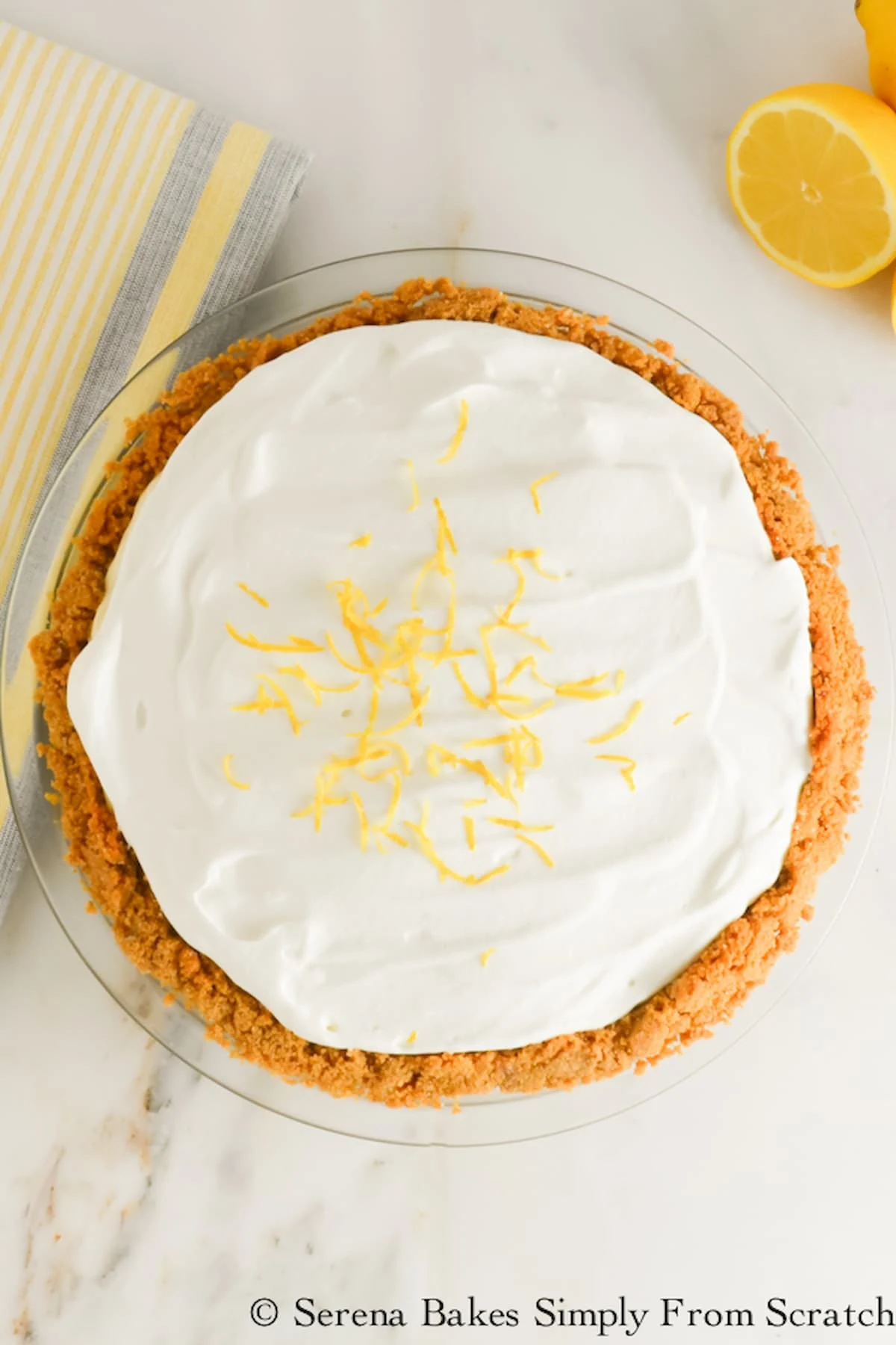 Lemon Pudding Cheesecake in a graham cracker pie crust topped with whipped cream and grated lemon zest.