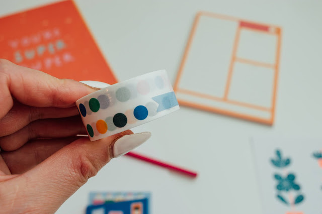 A hand holding up a roll of stickers with coloured dots