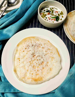 Serving appan with vegetable stew, spoon fork and appam in background