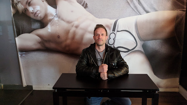 Image of Tom Ray at table in front of giant model in his underwear