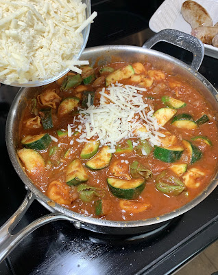 Grated cheese being added to a skillet of red sauce. Grated cheese being added to a skillet of red sauce.