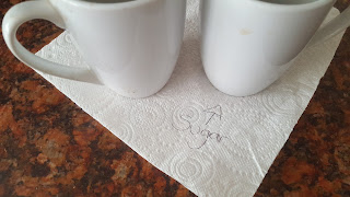 Two mugs of tea on a bit of Kitchen paper indicating which mug has sugar
