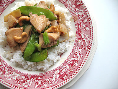 An overhead photo of cashew chicken on a red and white plate.