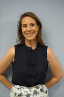 close-up of smiling Caucasian woman standing in front of wall with hands pressed against wall