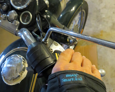 Close up of a hand in a glove holding a handlebar.