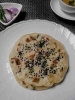 Serving kulcha in a plate, dal and onion slices in background