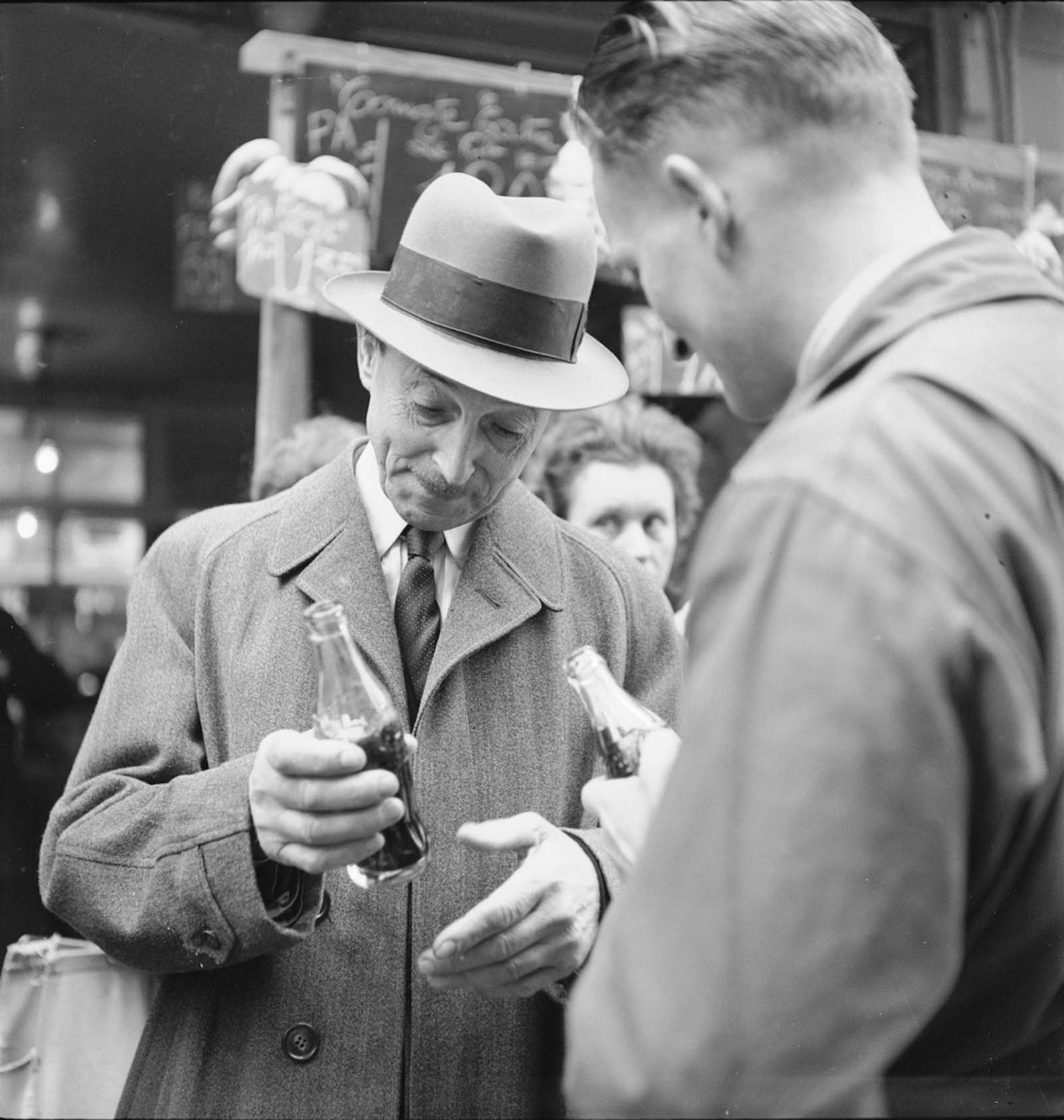 Számos azonosítatlan ember iszik üveg Coca-Cola-t Párizsban, Franciaországban. 