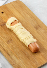Hot dog wrapped in crescent roll strips to make a mummy