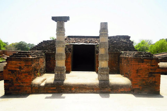 The remains of a brick temple, with wonderfully decorated stone pillars, at Nalanda