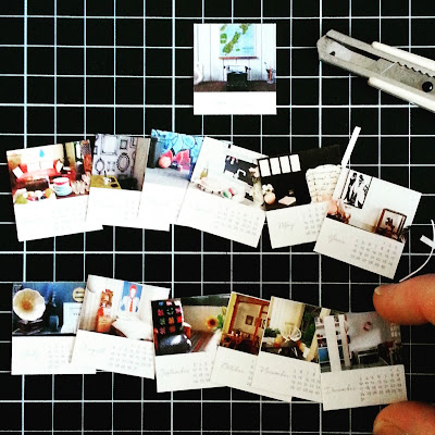 Pages of a miniature 2017 calendar on a cutting board with knife and fingers for size.