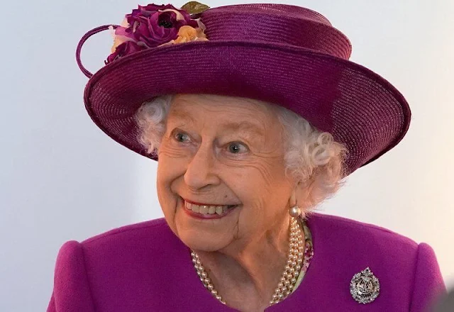 The Queen wore a floral print dress and purple coat and purple hat. diamond brooch