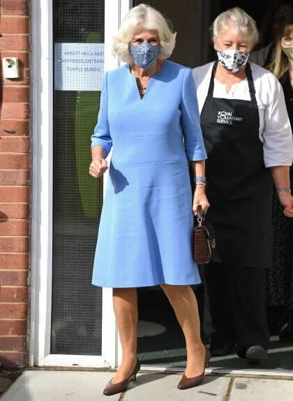 Camilla, Duchess of Cornwall wore a blue wool midi dress, and the mid-length chelsea trench coat from Burberry. British luxury brand Burberry