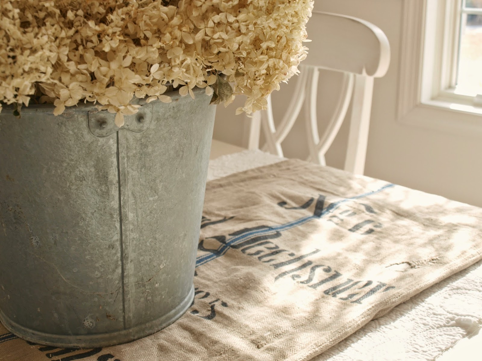 Antique grain sack as table runner in Nordic French dining room by Hello Lovely Studio. #grainsack #frenchcountry #frenchfarmhouse #galvanized #hydrange #diningroom