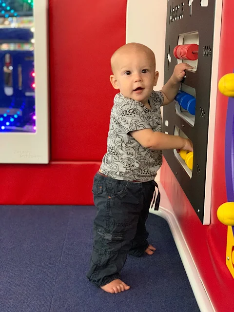7 month old baby boy standing up while holding on to a play abacus