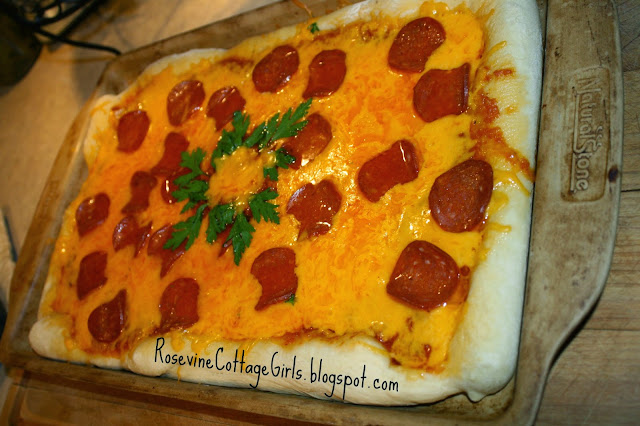 Making homemade pizza - photo of a cheese and pepperoni pizza in a rectangular stone cookie sheet with homemade sauce and cheddar cheese