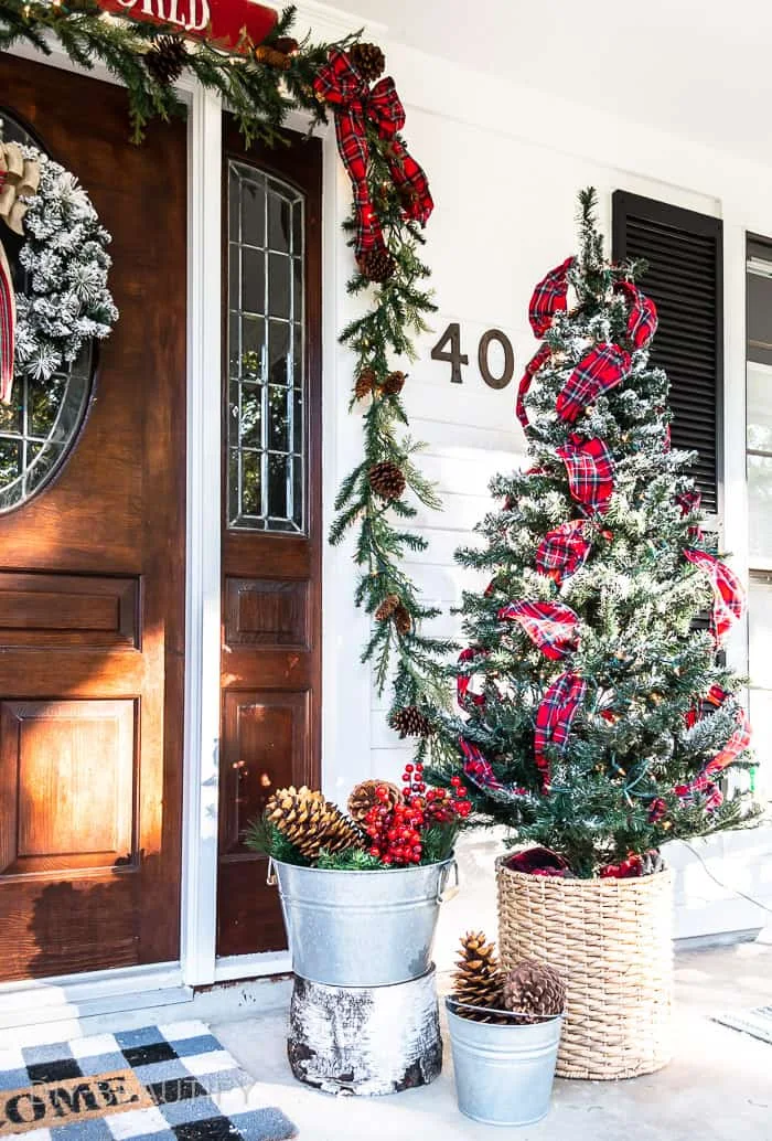 Christmas tree with plaid ribbon swags in basket on porch