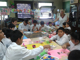 alumnos de diferentes escuelas en el taller de plástica. se observan recortes de hojas y materiales plásticos sobre las mesas