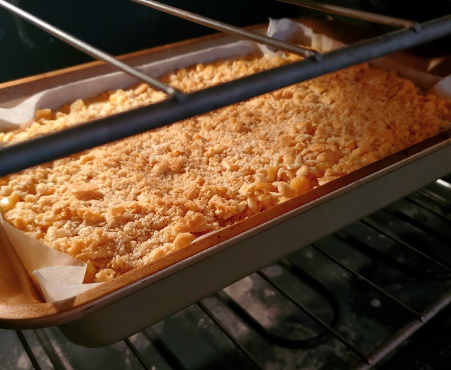 macaroni and cheese with chicken casserole baking in a metal casserole pan in the oven