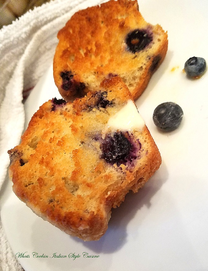 these are two muffins with blueberries on a white plate diner style grilled with butter