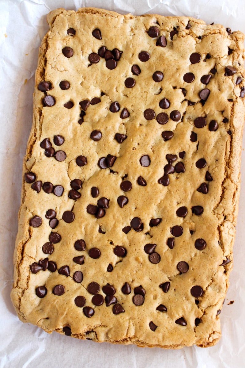Brown Butter Chocolate Chip Cookie Bars | The Two Bite Club | #chocolate #cookiebars Top view of brown butter cookie bars uncut on a piece of parchment paper.