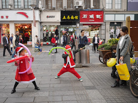 boy and girl wearing Santa and Mrs. Clause outfits pretending to hold weapons aimed at their mother