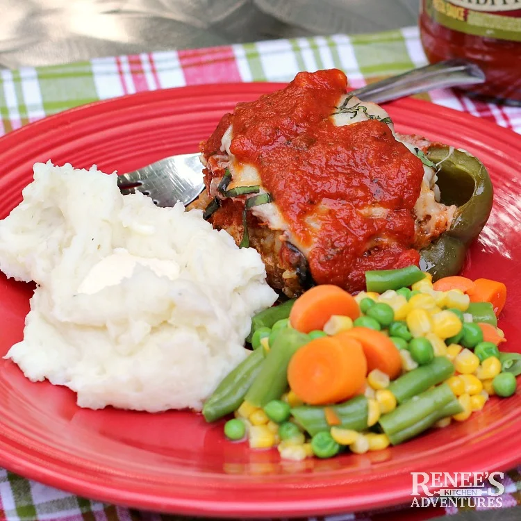 Italian Sausage Stuffed Peppers with Pasta Sauce by Renee's Kitchen Adventures on a red plate with a fork, mashed potatoes, and mixed vegetables. 