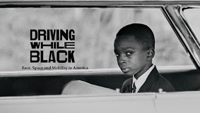 Close up of Ben Cheney in car with Driving While Black logo Driving While Black logo on photograph of young black boy in car