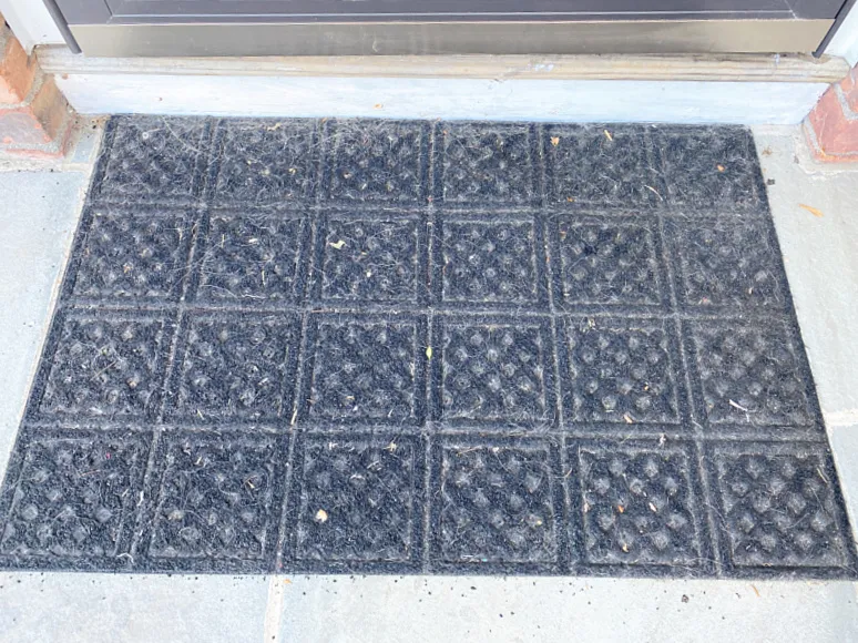 old outdoor mat with black pieces falling off