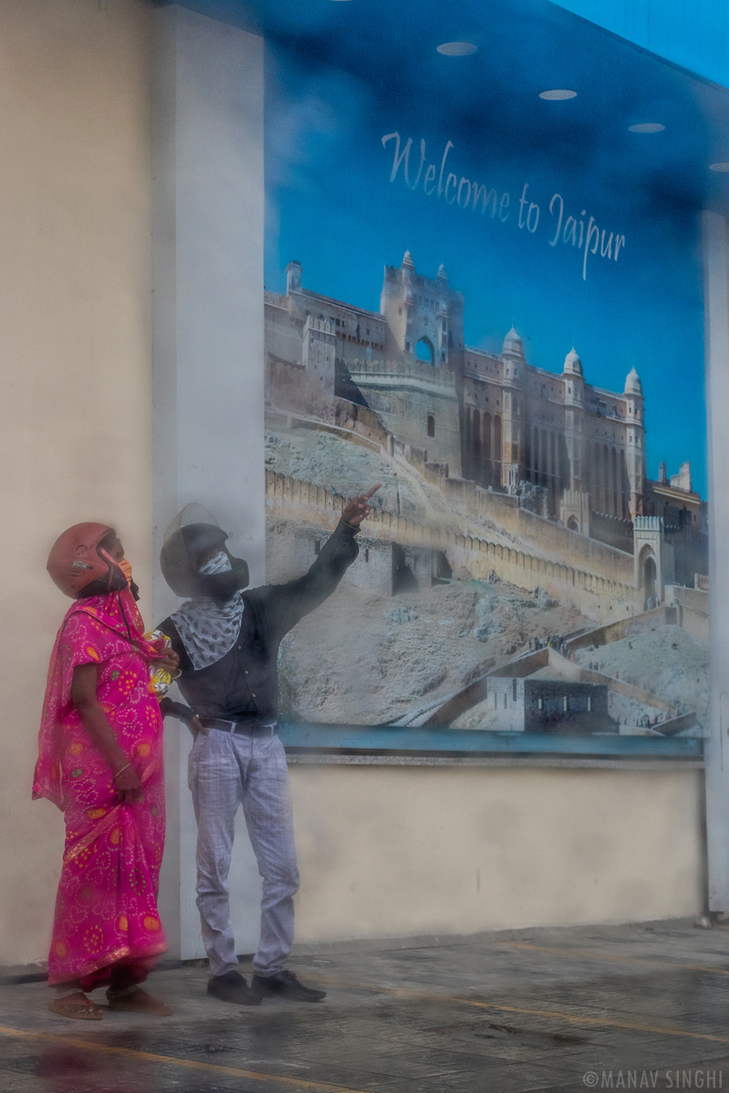 A Couple pointing towards the Rainbow, who was standing in the shade to get Protected from Rain Jaipur