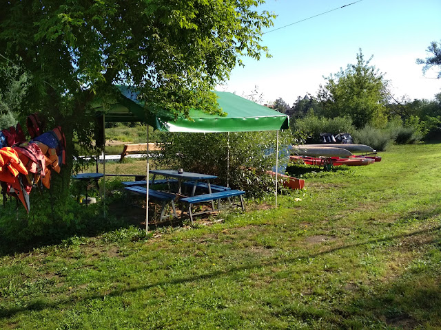 Niebieski kącik na Przystani Kowale. Po lewej kapoki, po prawej kajaki i tratwy.