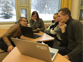 Neljä opettajaa tutkii läppäreiltä Quizlet-peliä luokkahuoneessa. Ikkunoista näkyy luminen maisema.